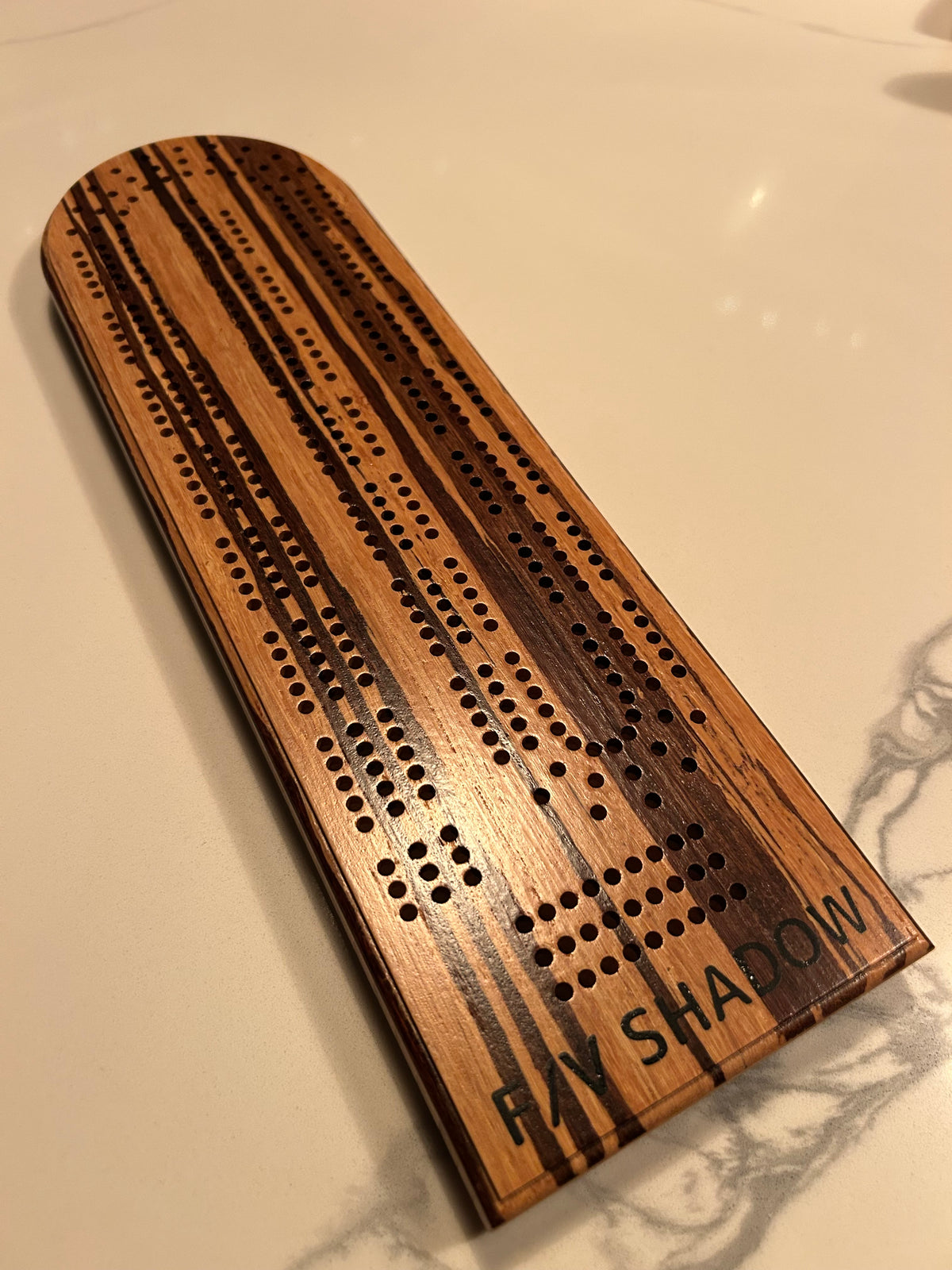 Curved hardwood cribbage board with three continuous peg-hole tracks and the name Ray Shadow engraved at the base.