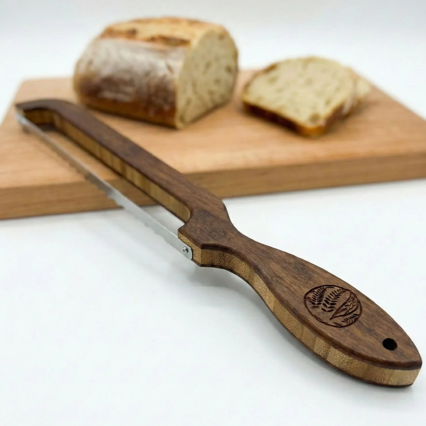 Wooden bread knife with a brand logo on a white background, with bread slices in the background.