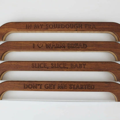 Four engraved sourdough bread knives reading In My Sourdough Era, I Love Warm Bread, Slice Slice Baby, and Don't Get Me Started.
