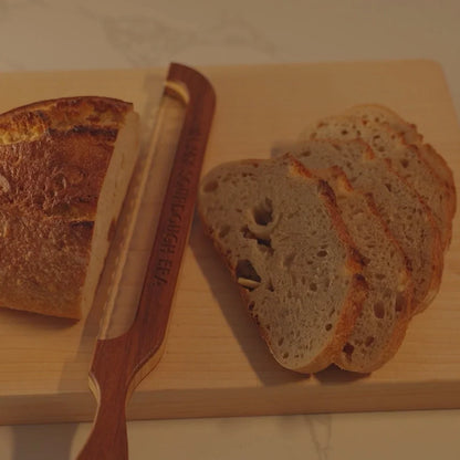 Clean, even slices of sourdough bread cut with a Loreto Studio bread knife on a wooden cutting board.